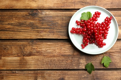 Photo of Delicious ripe red currants on wooden table, flat lay. Space for text