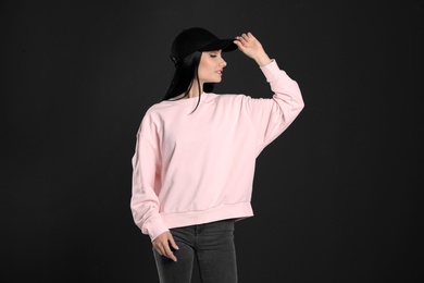 Photo of Portrait of young woman in sweater on black background. Mock up for design