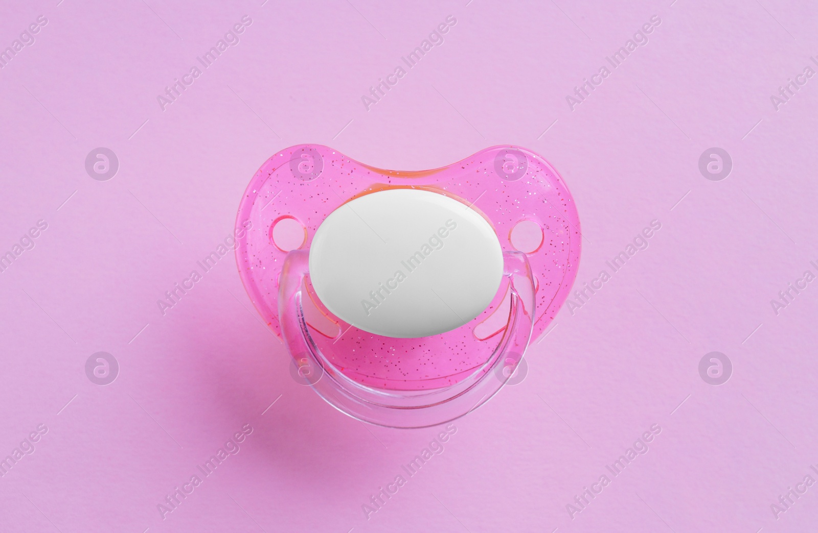 Photo of New baby pacifier on pink background, top view