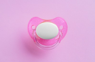 New baby pacifier on pink background, top view