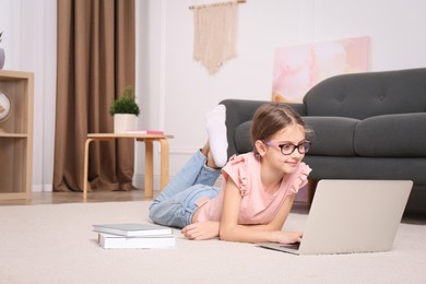 Photo of Girl with laptop and books lying on floor at home