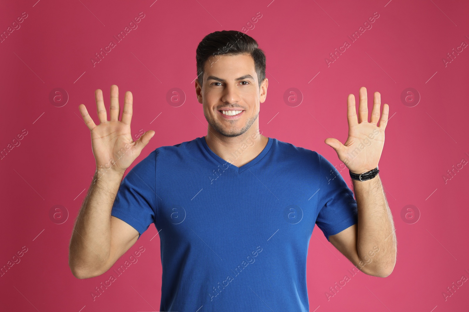 Photo of Man showing number ten with his hands on pink background