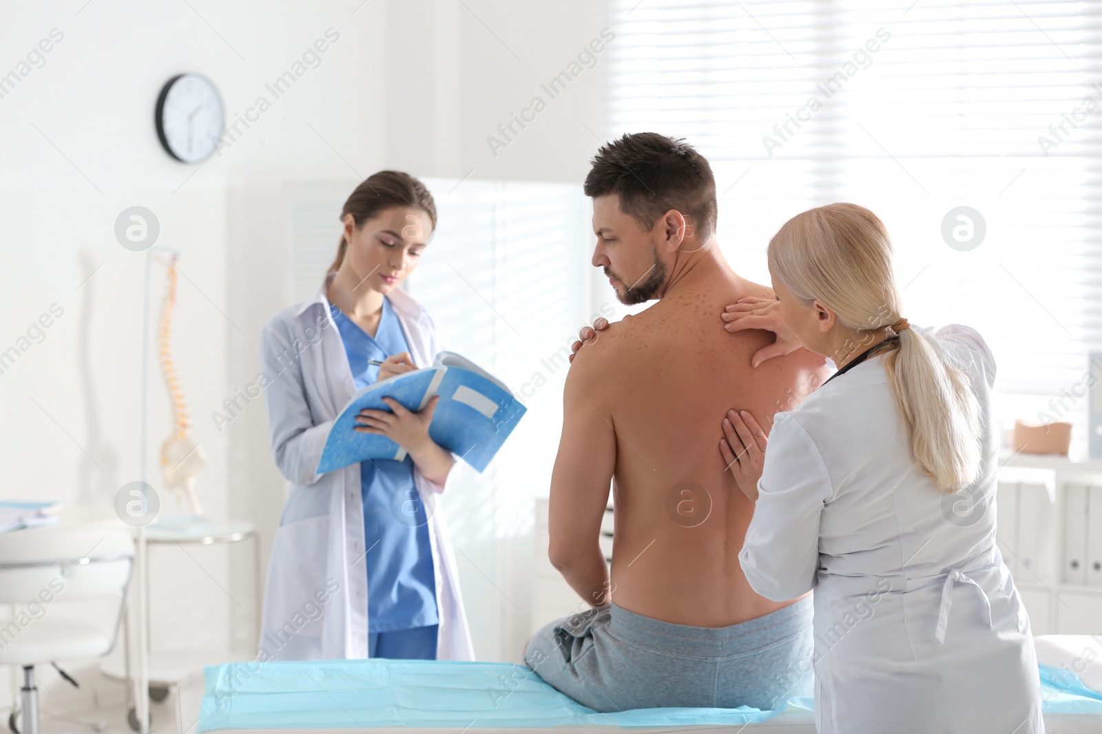 Photo of Female orthopedist examining patient's back in clinic