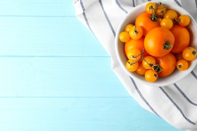 Photo of Ripe yellow tomatoes on light blue wooden table, flat lay. Space for text