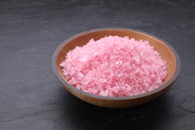 Photo of Bowl with pink sea salt on black table, closeup