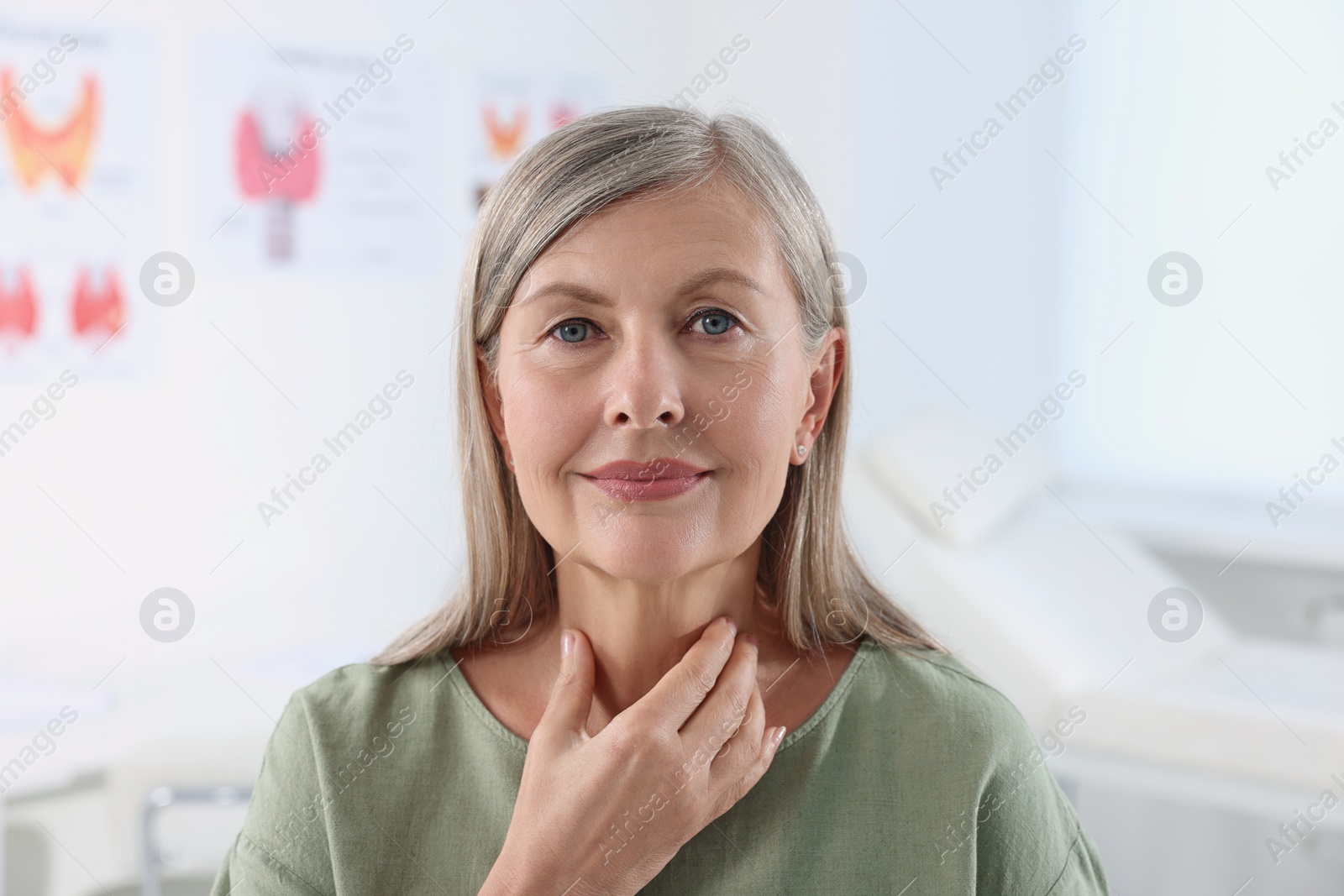 Photo of Endocrine system. Senior woman doing thyroid self examination indoors