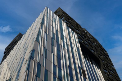 Photo of Exterior of beautiful modern skyscraper against blue sky, low angle view