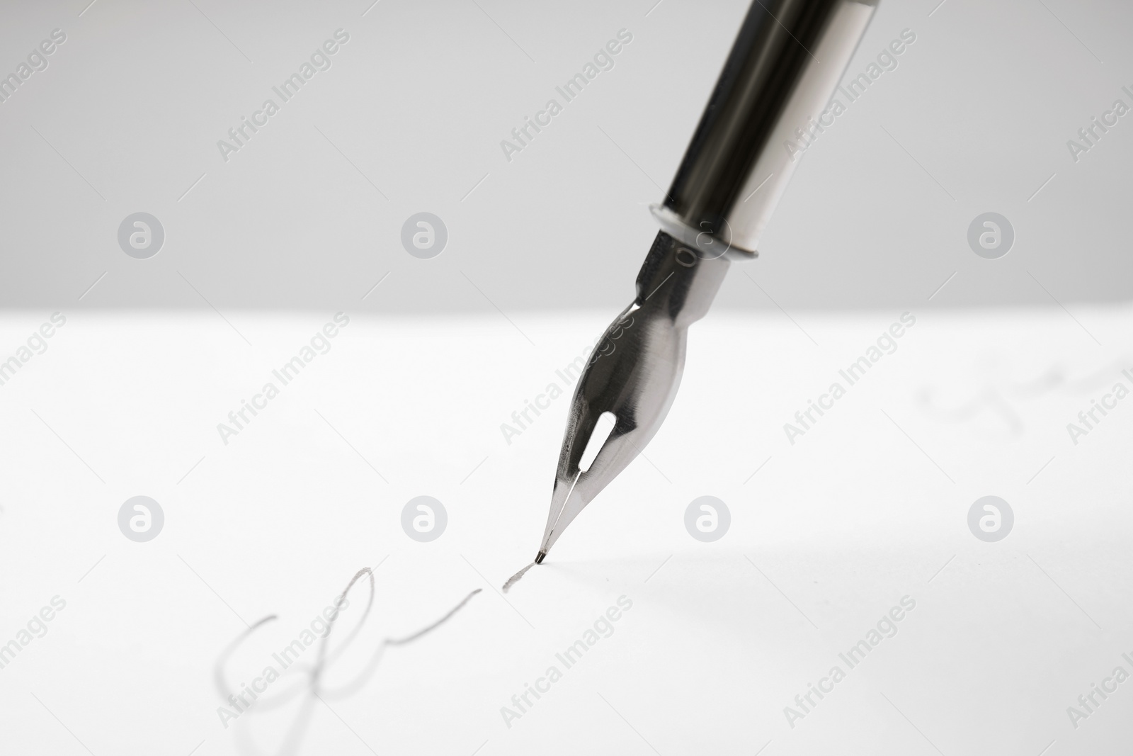 Photo of Signing on sheet of paper with fountain pen against light grey background, closeup. Space for text