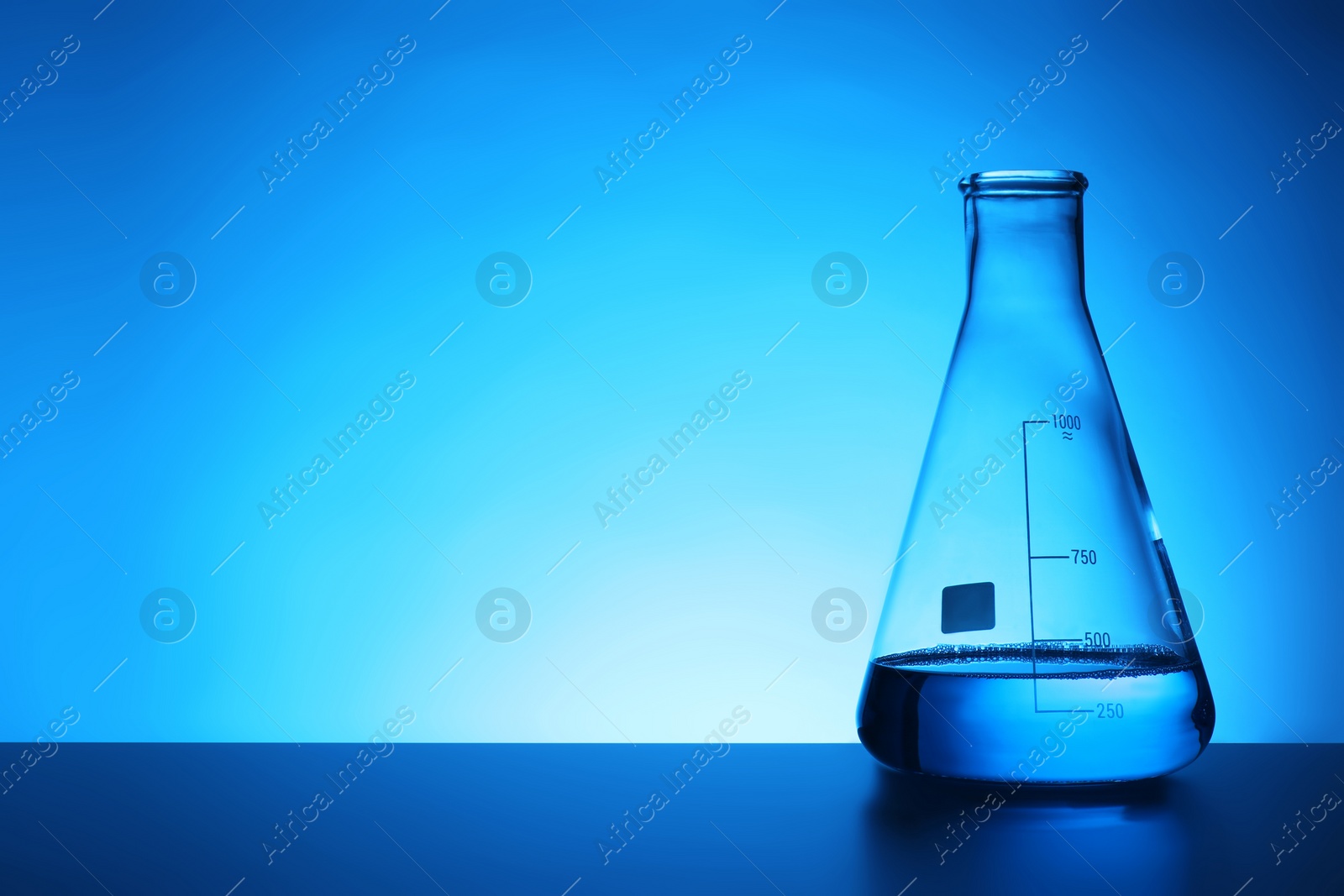 Photo of Conical flask with liquid on table against color background. Chemistry laboratory glassware