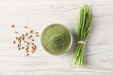 Photo of Wheat grass powder in bowl, seeds and fresh sprouts on white wooden table, flat lay