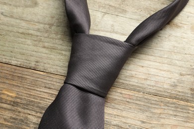 Photo of One necktie on light wooden table, top view