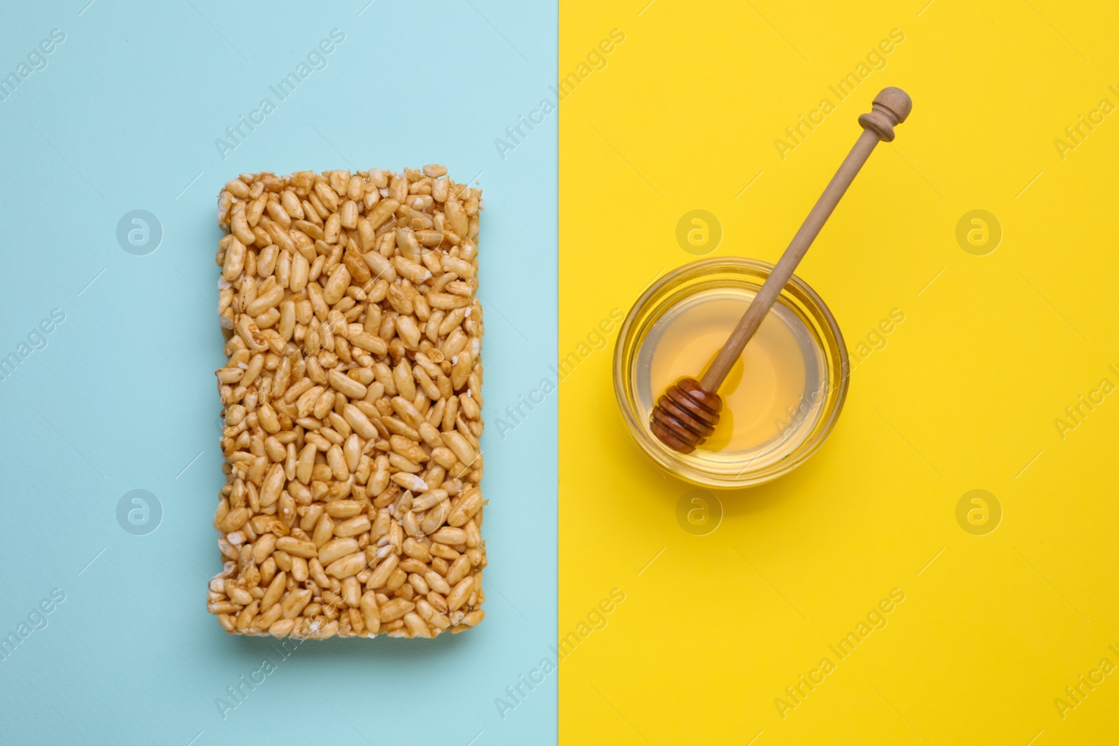 Photo of Puffed rice bar (kozinaki) and honey on color background, flat lay