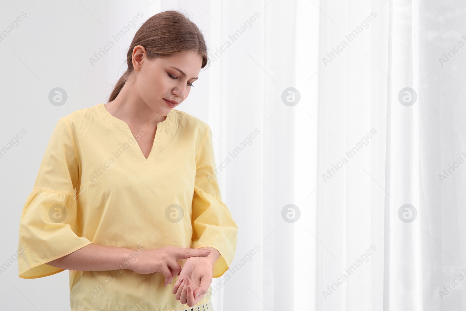 Photo of Young woman checking pulse on light background
