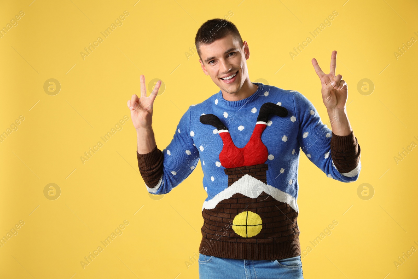 Photo of Portrait of happy young man in Christmas sweater on yellow background