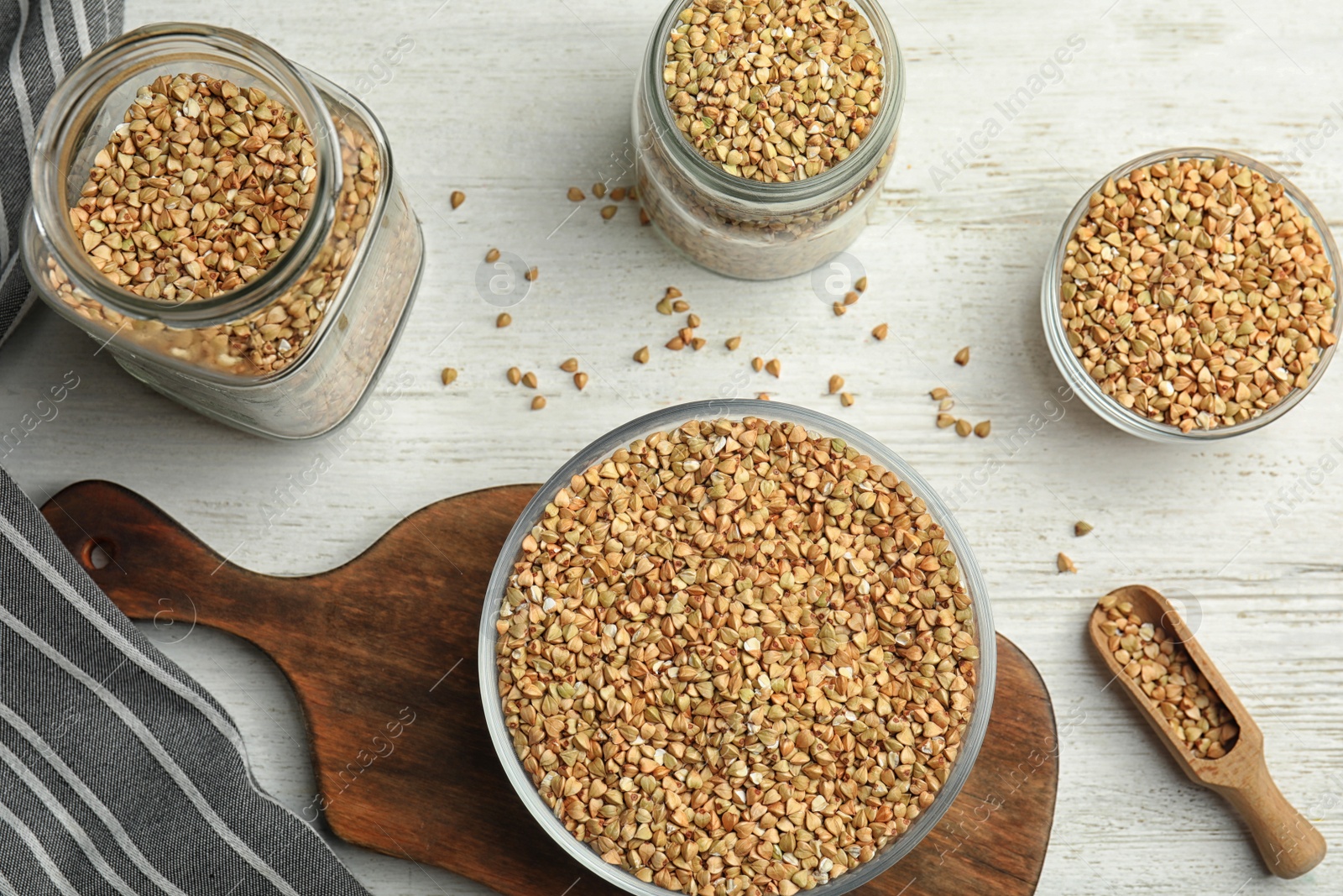 Photo of Uncooked green buckwheat grains on white wooden table, flat lay