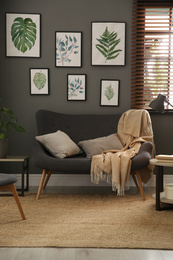 Beautiful artworks and comfortable sofa in stylish room. Interior design
