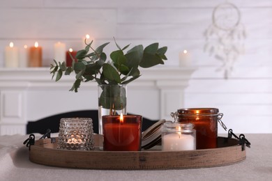 Photo of Tray with beautiful burning candles and vase on table indoors