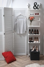 Photo of Dressing room with folding screen and decorative ladder. Contemporary interior design