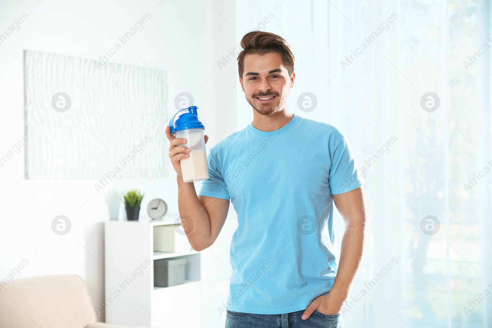 Photo of Young man with bottle of protein shake at home