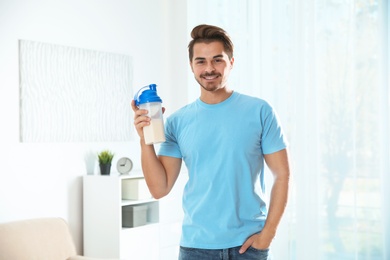 Photo of Young man with bottle of protein shake at home