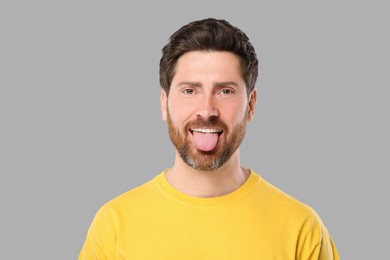 Photo of Man showing his tongue on gray background