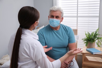 Photo of Doctor talking to senior man with protective mask at nursing home