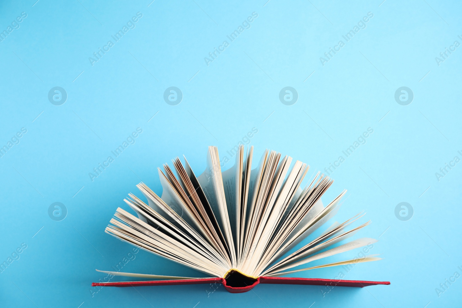 Photo of Hardcover book on light blue background, top view