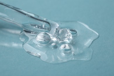 Pipette with cosmetic serum on light blue background, closeup