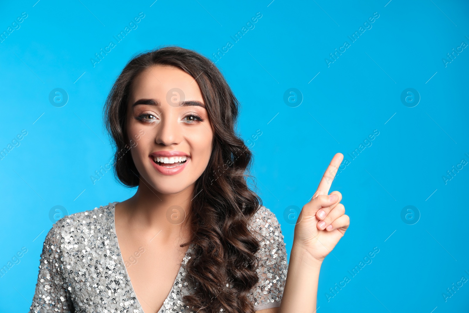 Photo of Beautiful young woman wearing elegant dress on blue background. Christmas party