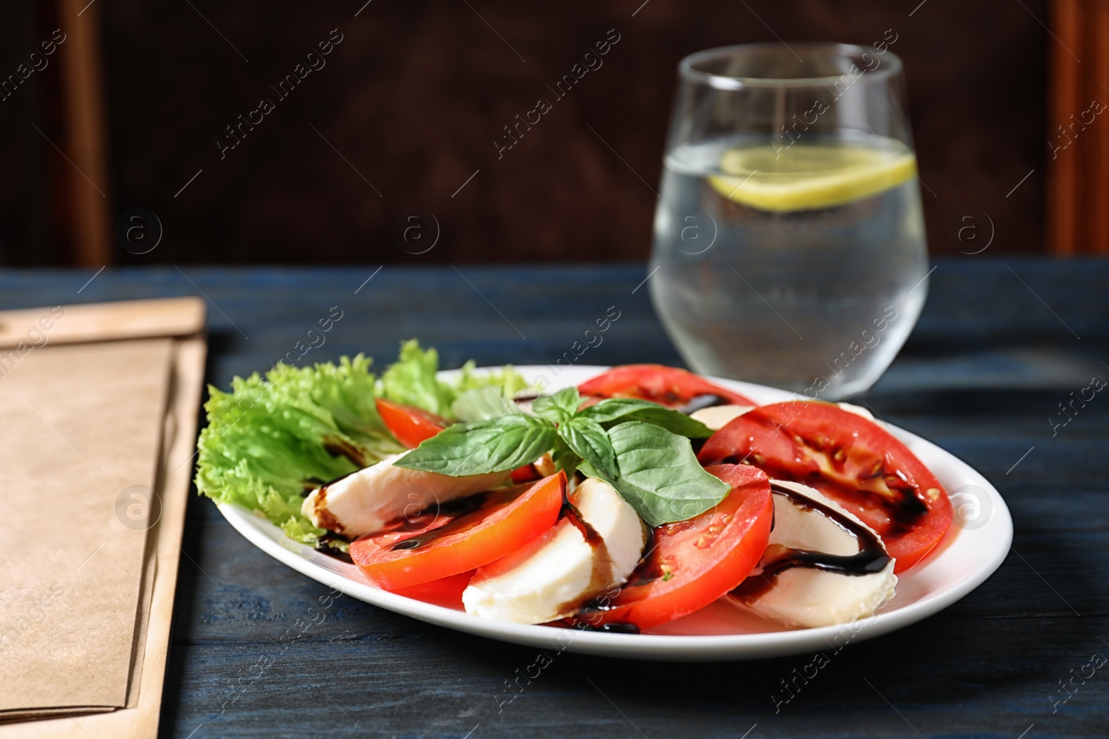 Photo of Plate with delicious fresh salad and glass of drink on table