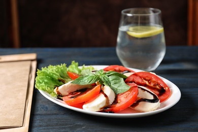 Photo of Plate with delicious fresh salad and glass of drink on table