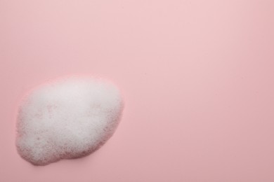 Photo of Drop of fluffy soap foam on pink background, top view. Space for text