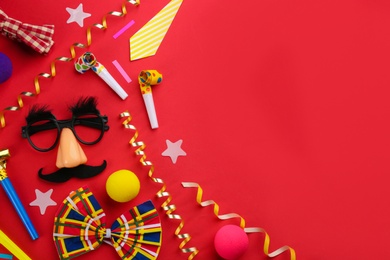 Flat lay composition with clown's accessories on red background. Space for text