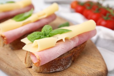 Delicious sandwiches with ham and cheese on wooden board, closeup