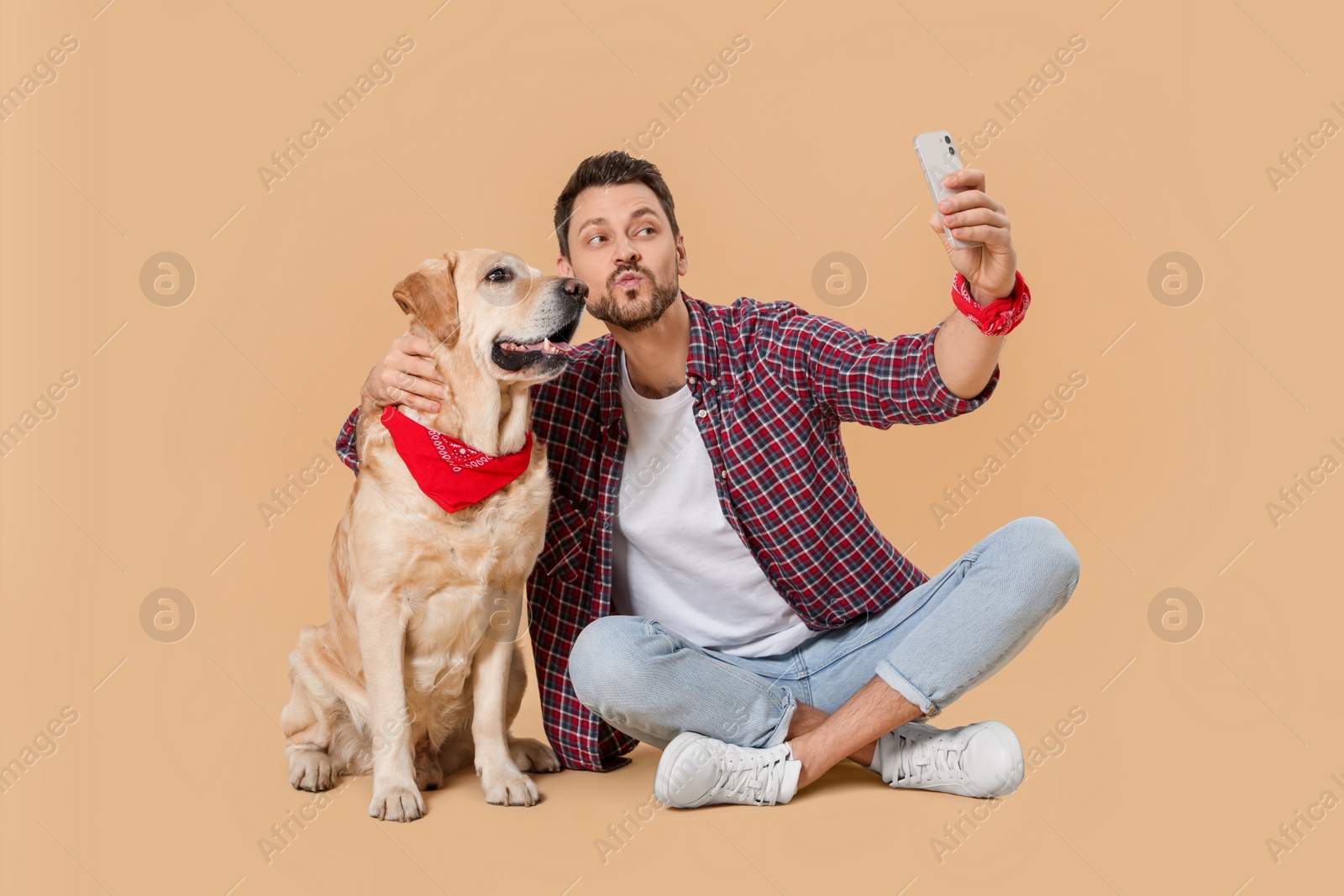 Photo of Man taking selfie with his cute Labrador Retriever on beige background