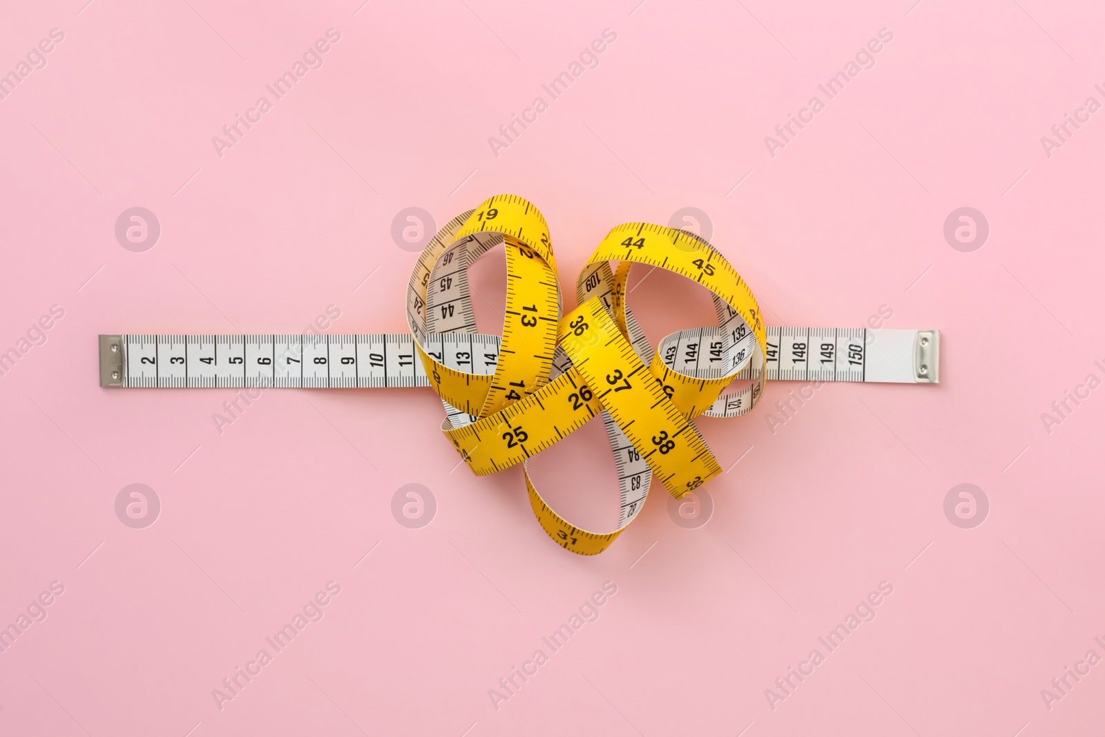 Photo of Measuring tape on pink background, top view