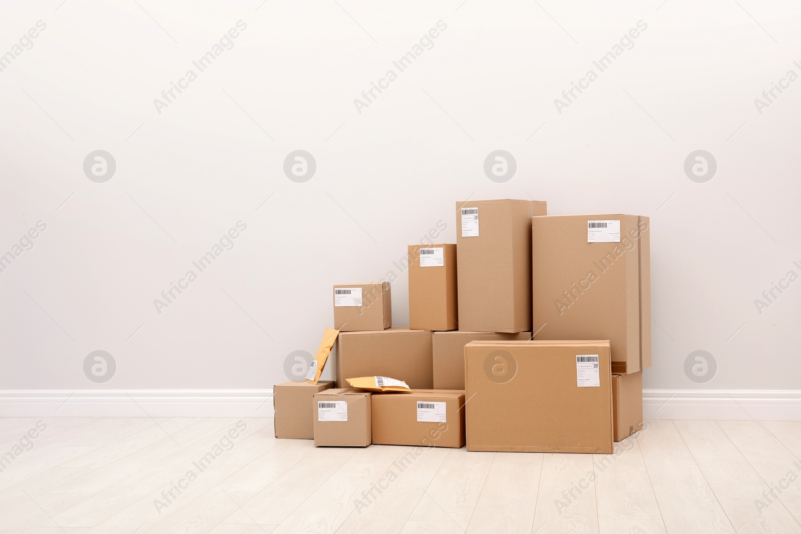 Photo of Stacked parcel boxes on floor against light wall