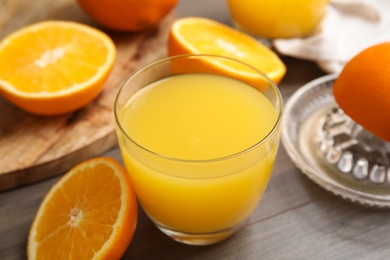 Fresh ripe oranges and glass of juice on wooden table, closeup