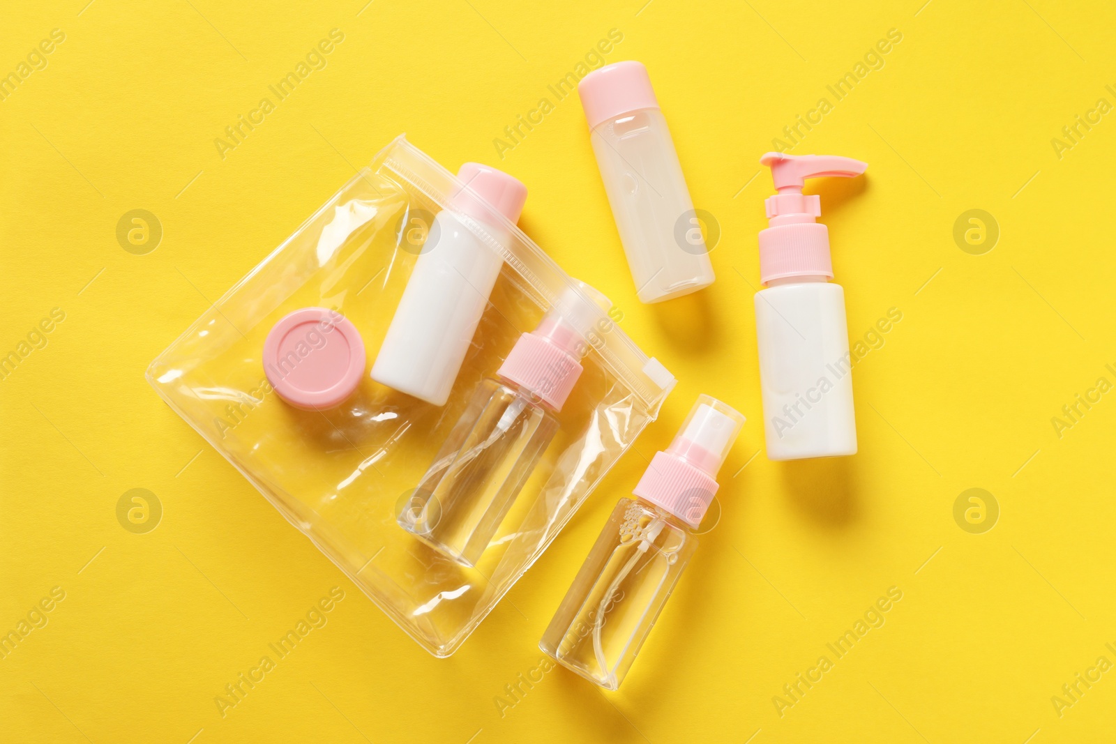 Photo of Plastic bag with cosmetic travel kit on yellow background, flat lay. Bath accessories