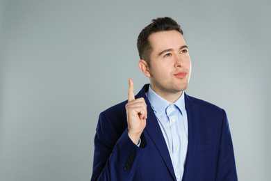 Portrait of emotional young businessman on grey background