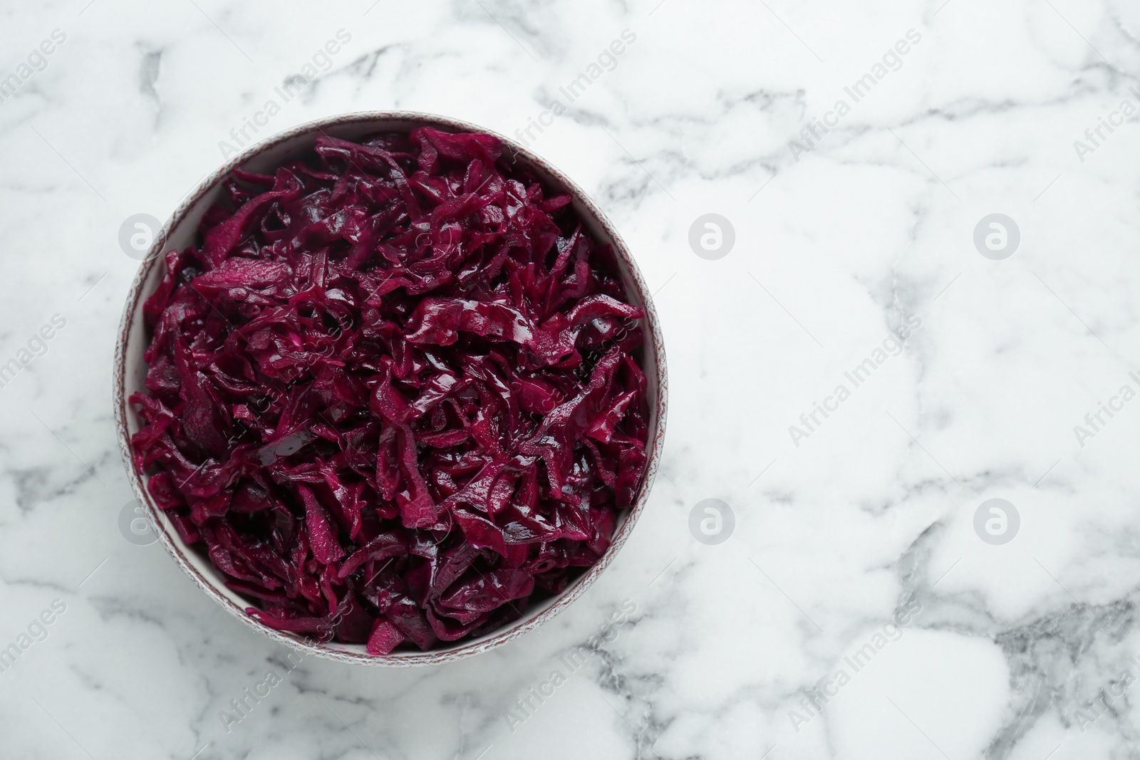 Photo of Tasty red cabbage sauerkraut on white marble table, top view. Space for text