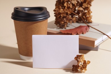 Photo of Dried hortensia flowers, sheet of paper and cardboard cup on beige table. Space for text