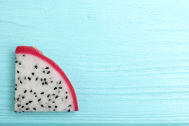 Photo of Slice of delicious dragon fruit (pitahaya) on light blue wooden table, top view. Space for text