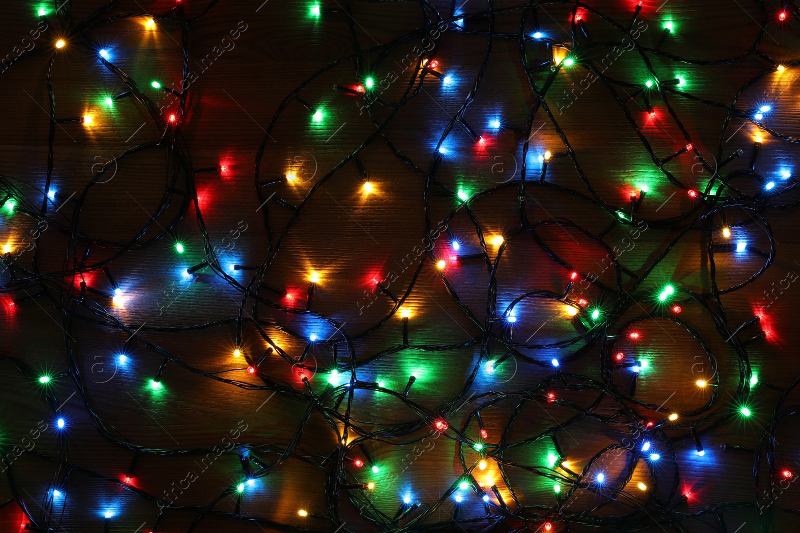 Photo of Colorful Christmas lights on wooden table, top view