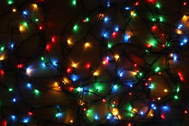 Photo of Colorful Christmas lights on wooden table, top view