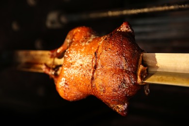 Photo of Grilling whole delicious duck in rotisserie machine, closeup