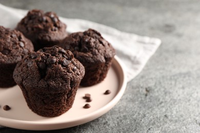 Photo of Delicious chocolate muffins on grey textured table, closeup and space for text