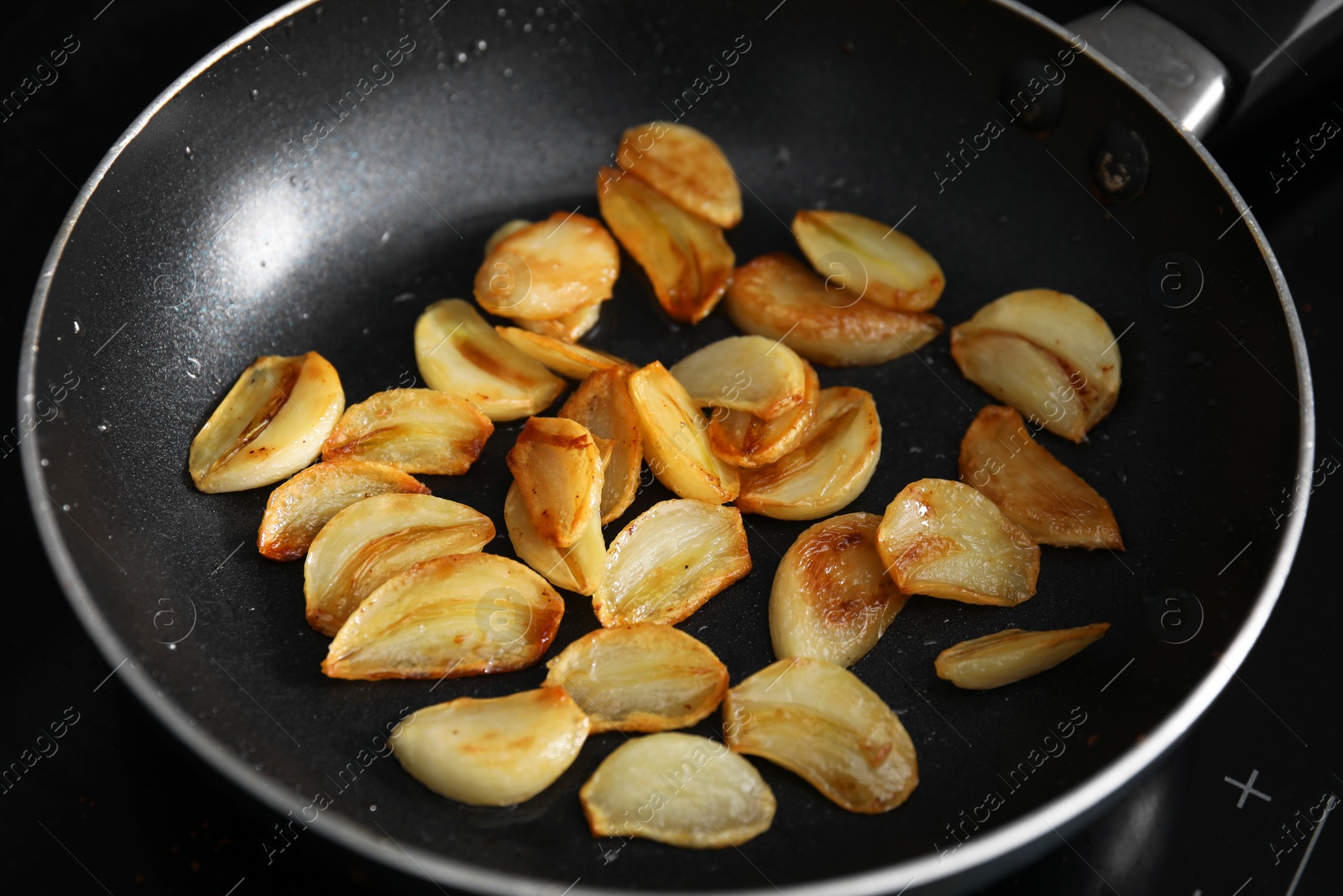 Frying pan with fried garlic cloves, closeup Photo of Frying pan with fried garlic cloves, closeup