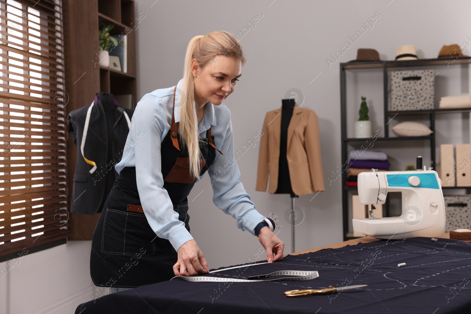 Photo of Dressmaker with measuring tape working in atelier