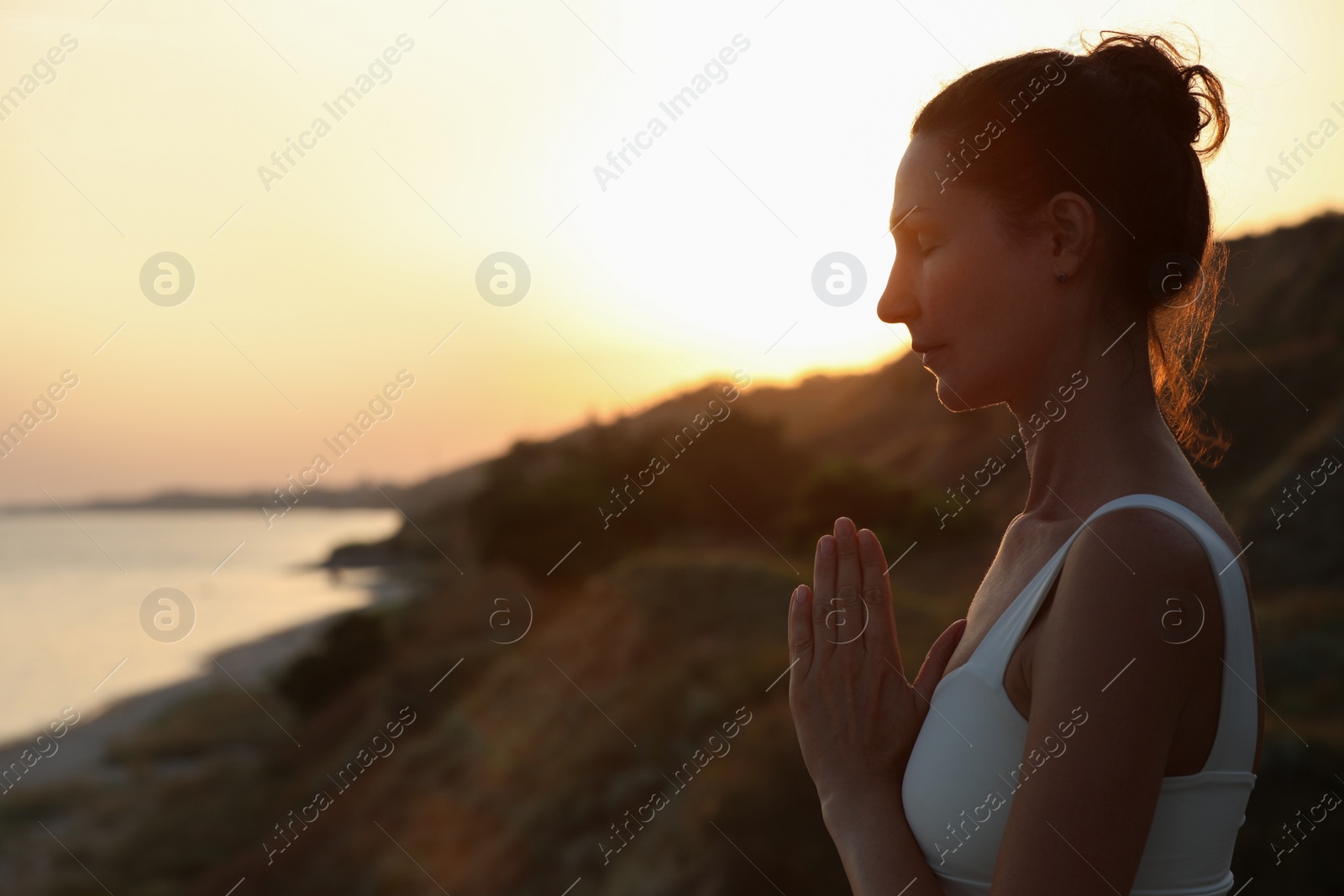 Photo of Mature woman meditating outdoors in evening. Space for text